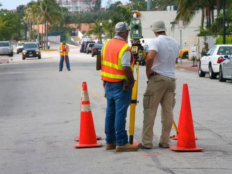 Survey crew collecting measurements while evaluating neighboring parcels for a future lot combination project.
