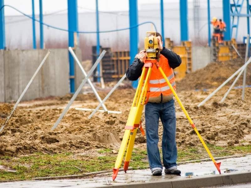 Surveyor collecting site measurements during a redevelopment project involving an existing property.